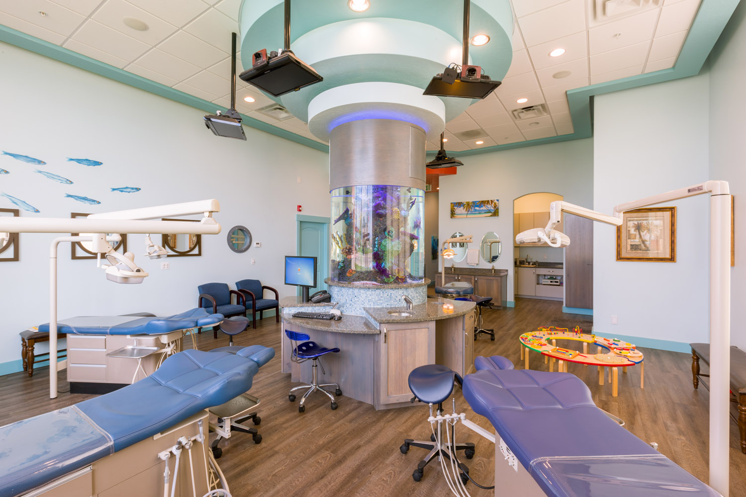 picture of your dentist: open bay dental treatment area with tvs on the ceiling and round aquarium in the center